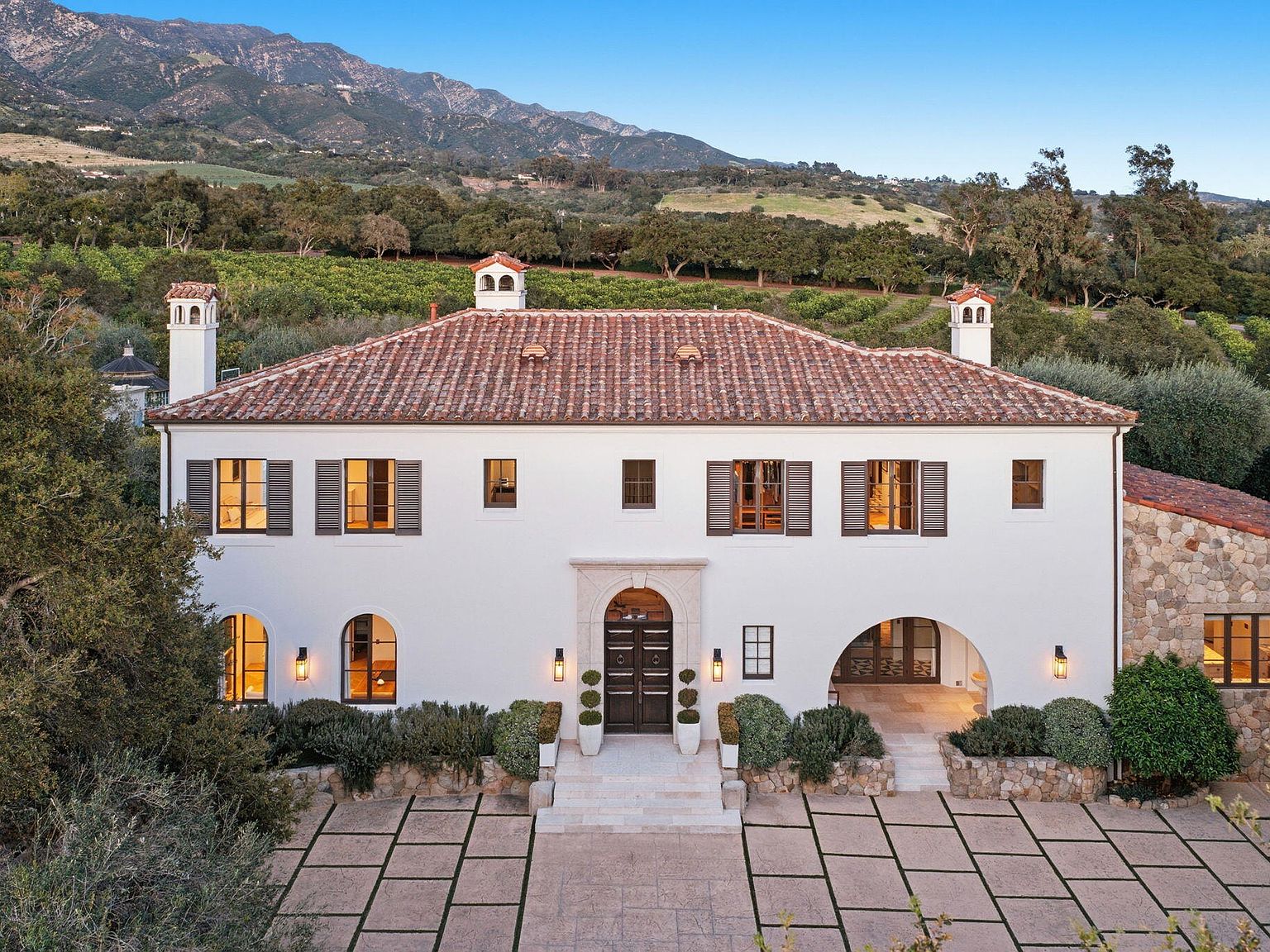 Front elevation of the Mediterranean villa with red tile roof and mountain backdrop