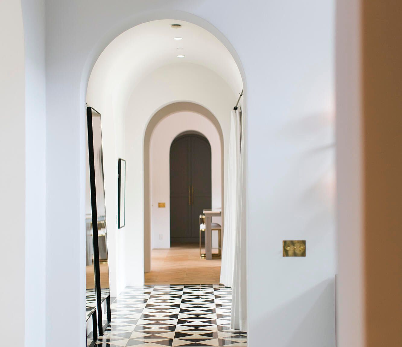 Vaulted plaster archway with checkerboard marble floor leading into the residence