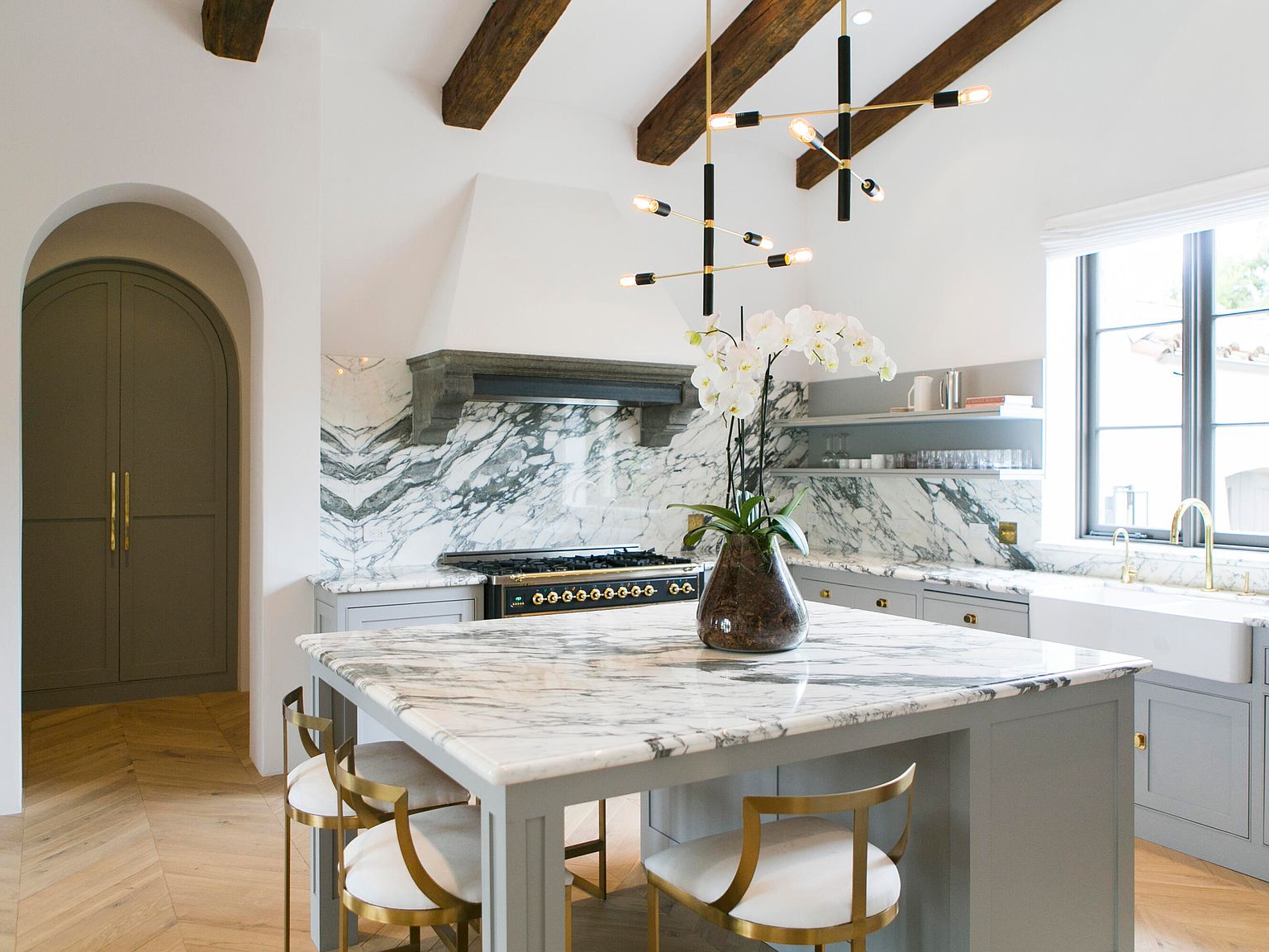 Chef's kitchen with veined marble island, ILVE range, and exposed timber ceiling beams